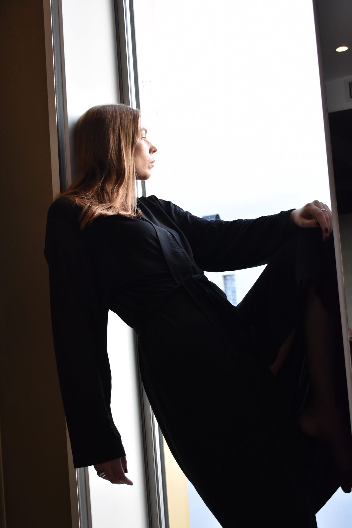 Sidobild av modell i svart morgonrock Zoe vid fönster
